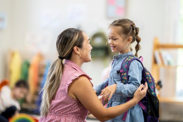 Mum and daughter saying 'bye' at childcare drop off