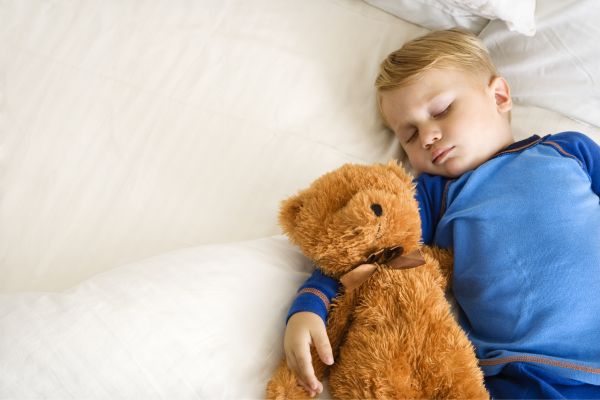 Toddler sound asleep with comfort teddy toy. 