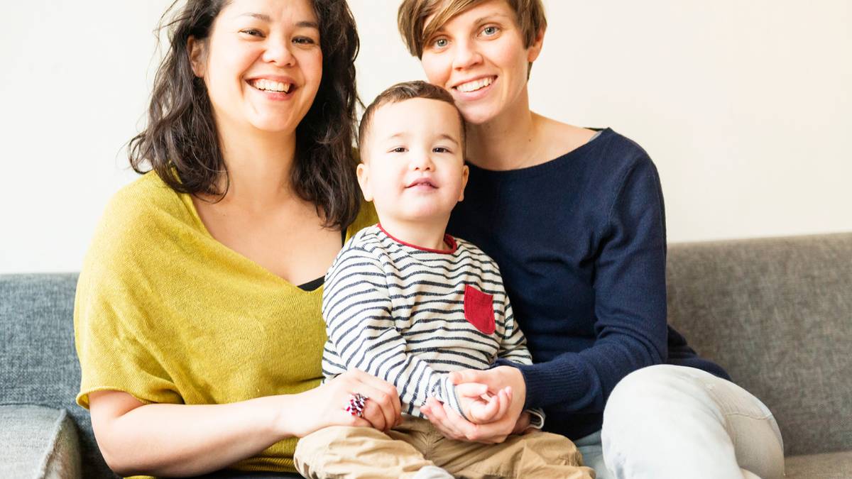 Two women sit with child on couch.