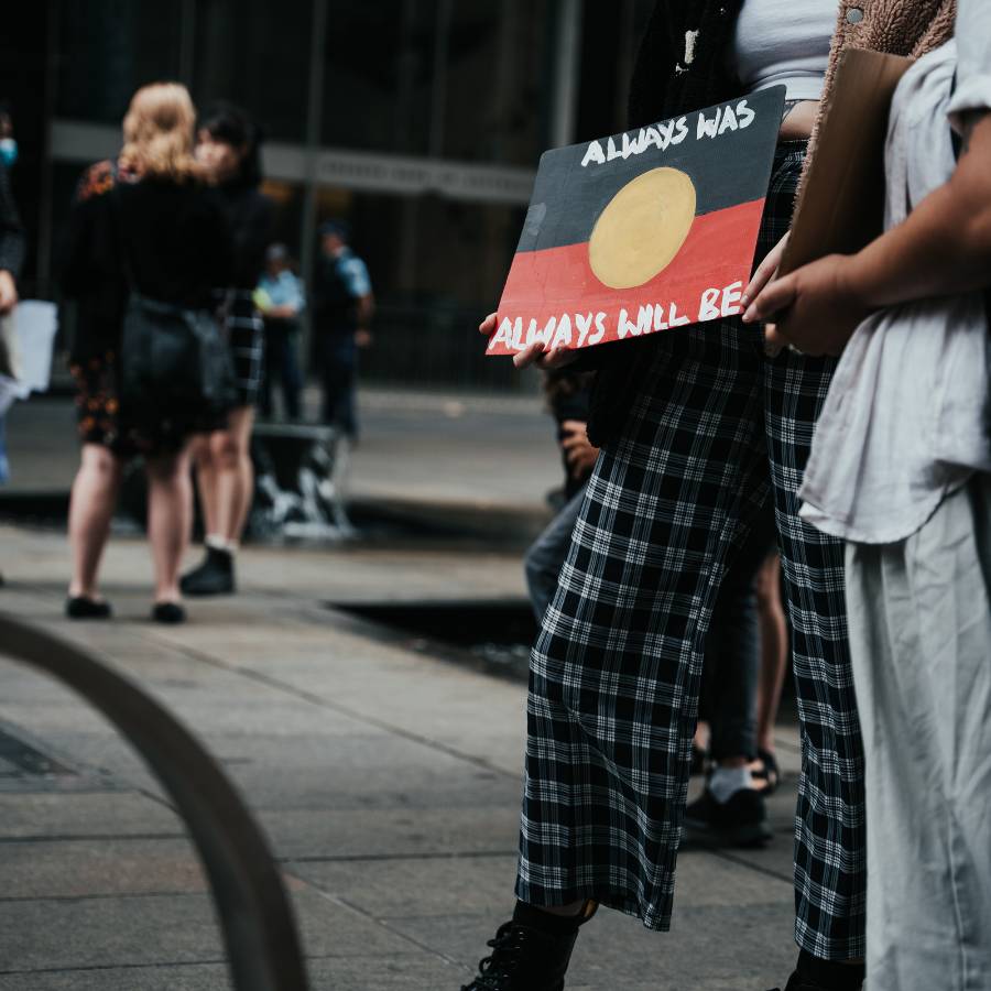 Women holds placard at Invasion Day protest